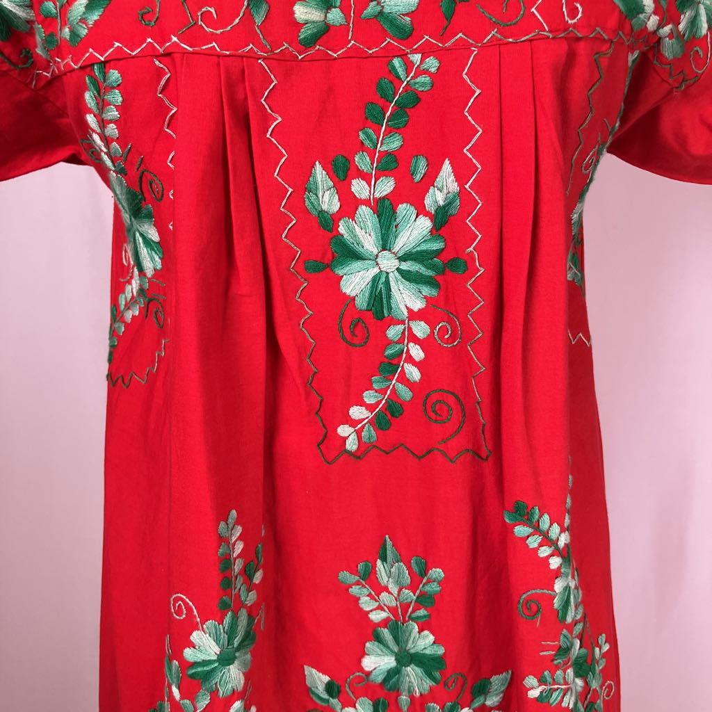 Red garment with green floral embroidery on a pink background