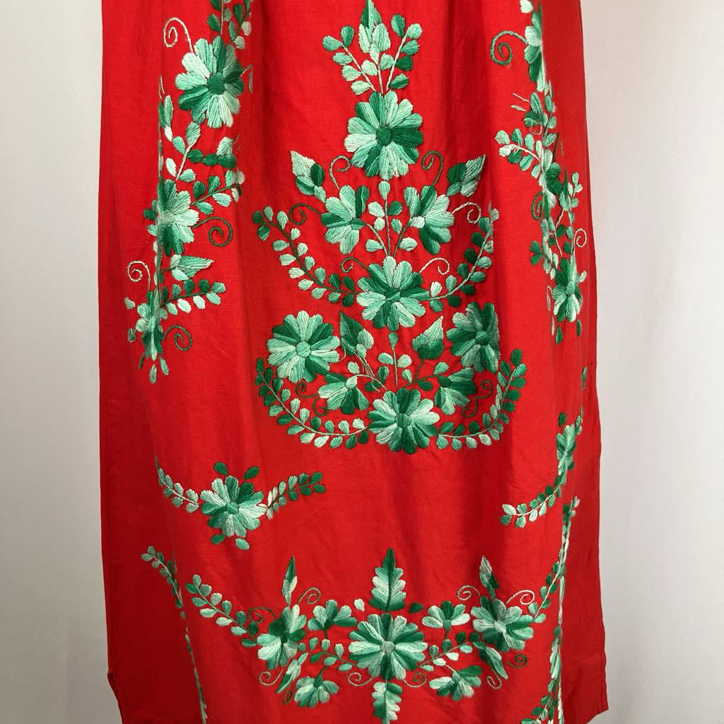 Red fabric with green floral embroidery on a plain background