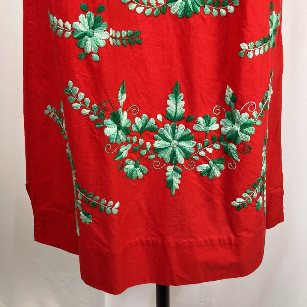 Red garment with green floral embroidery on a white background