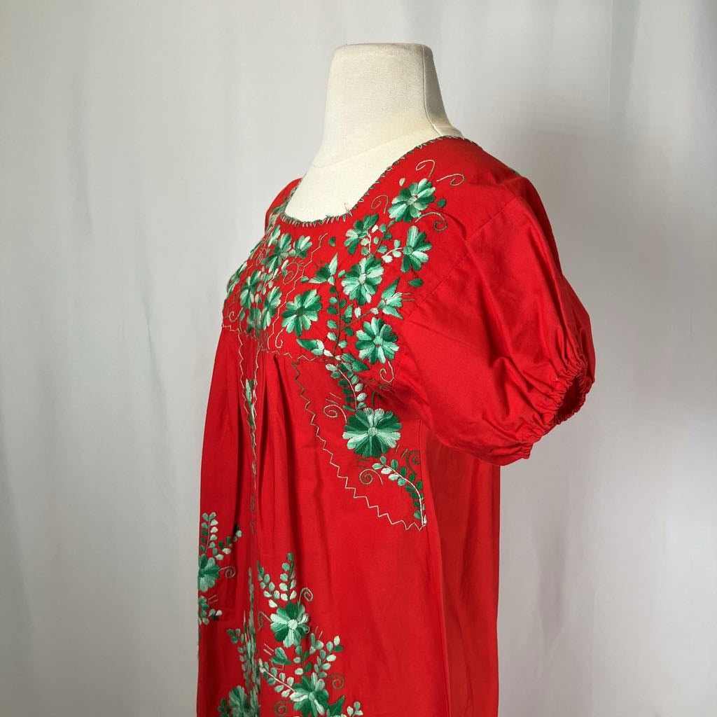 Red blouse with green floral embroidery on a mannequin against a white background
