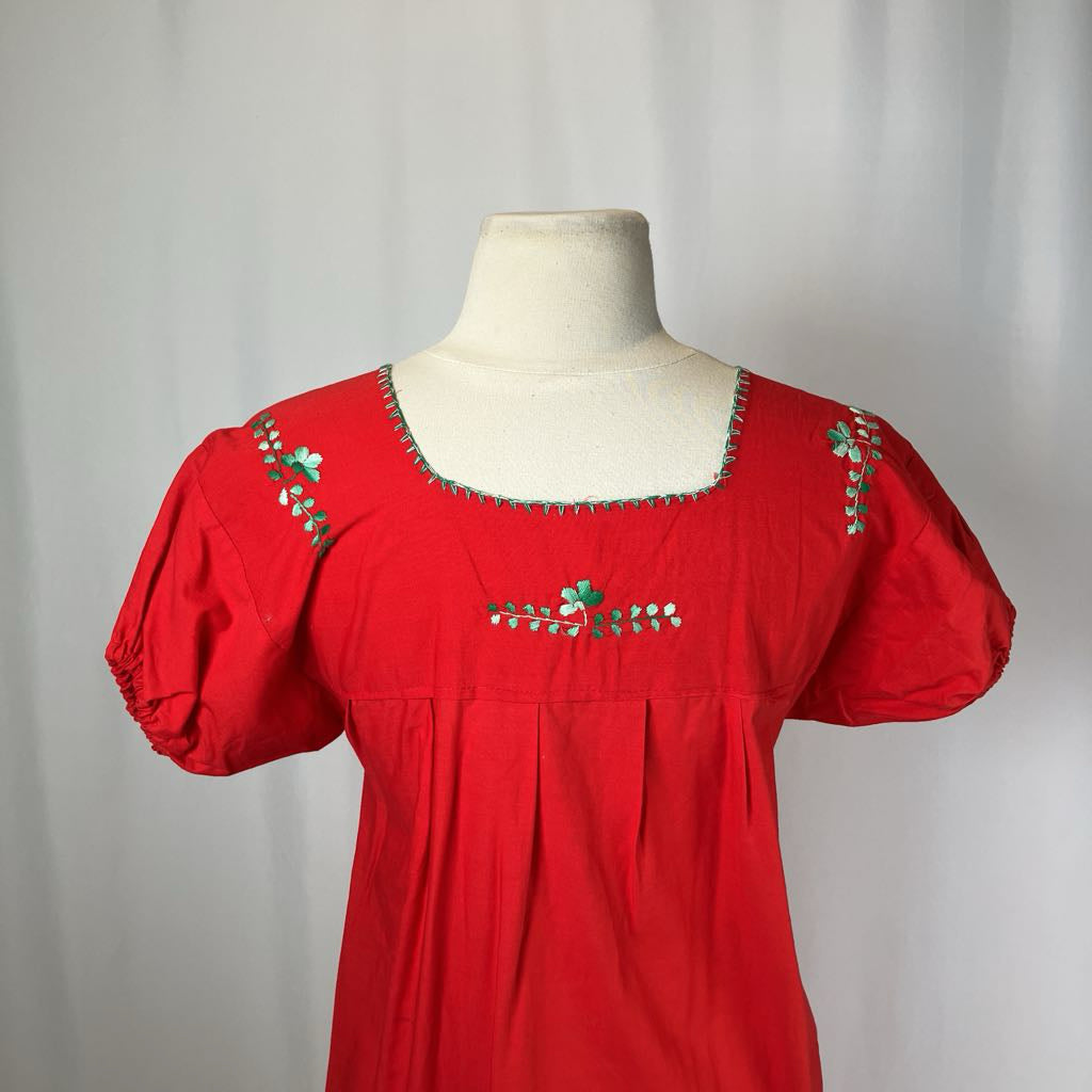 Red dress with floral embroidery on a mannequin against a plain background