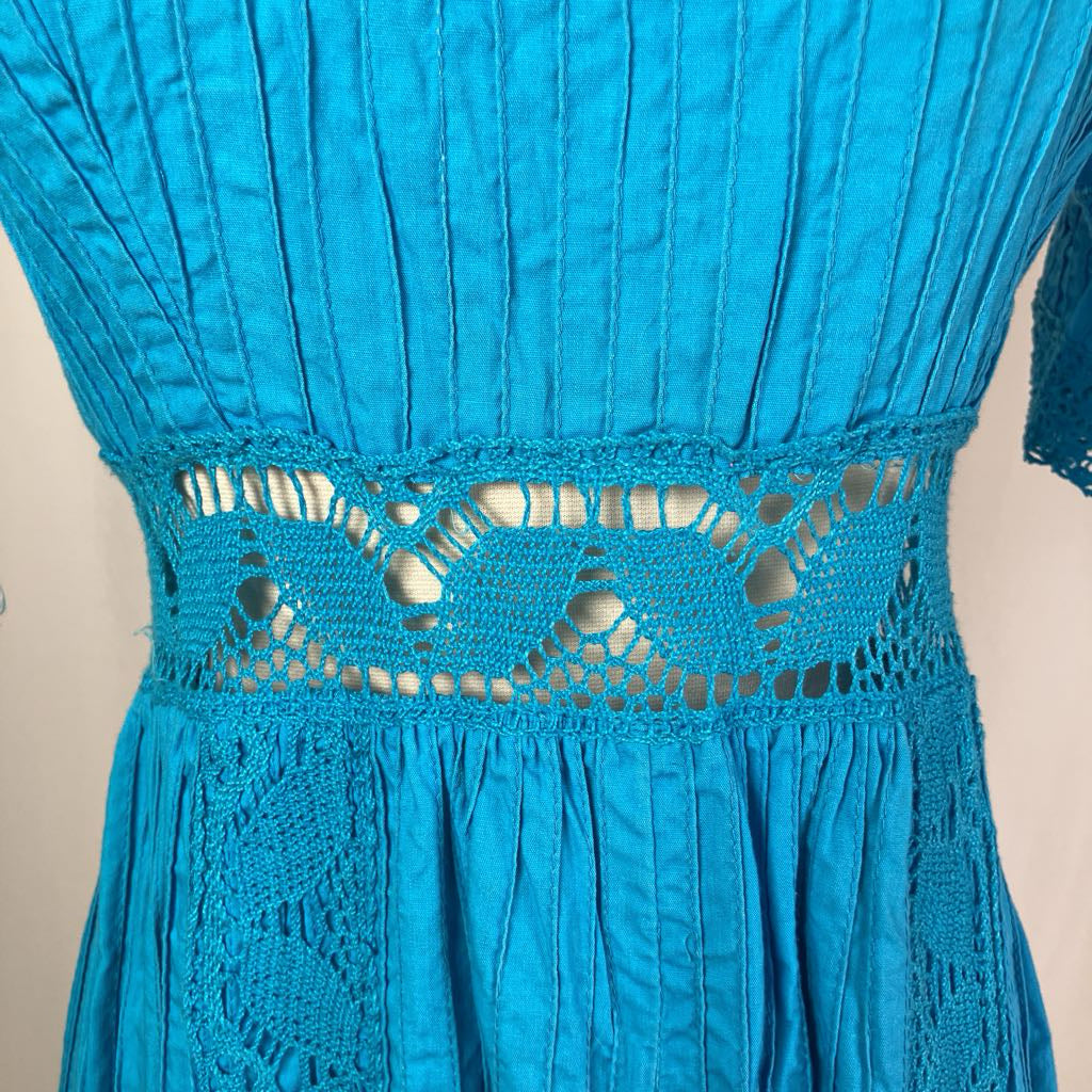 Close-up of a blue dress with intricate lace detailing on a beige background