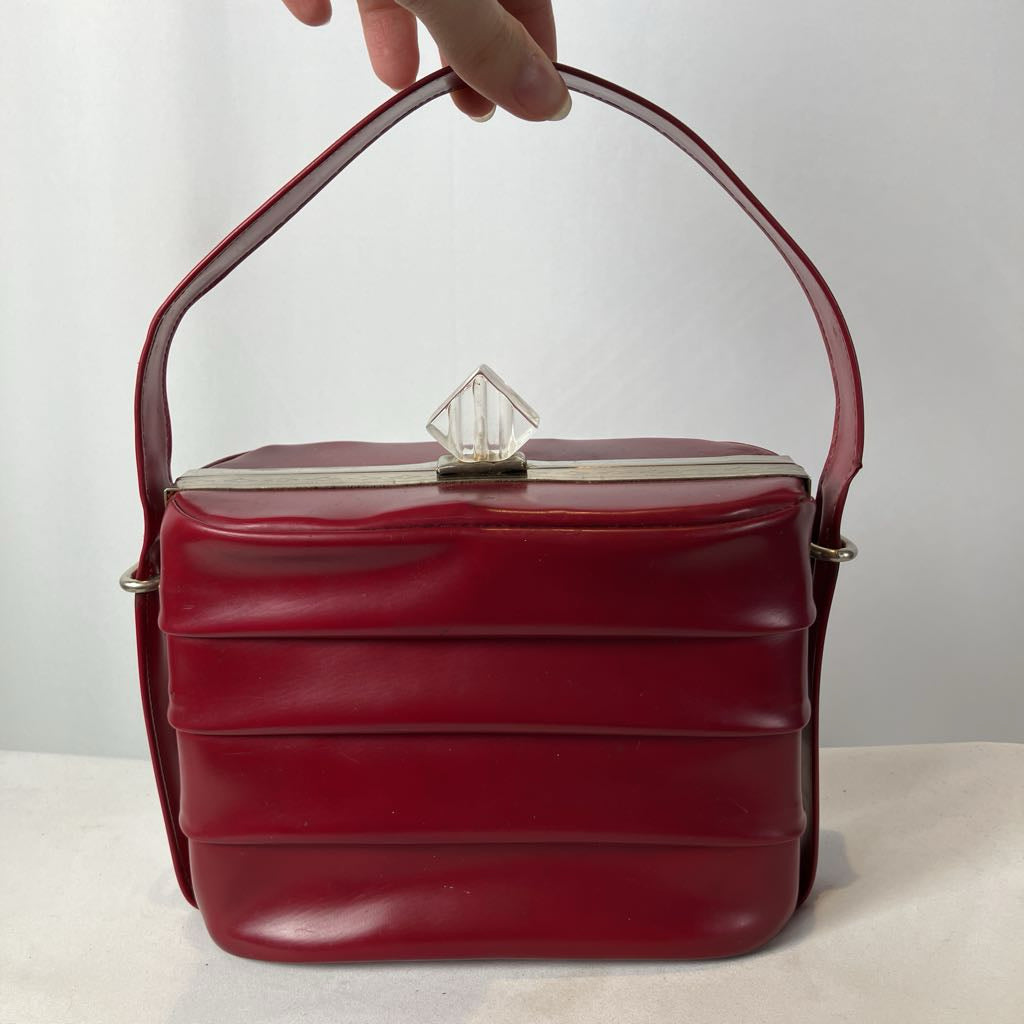 Red handbag with a clear crystal clasp on a white background