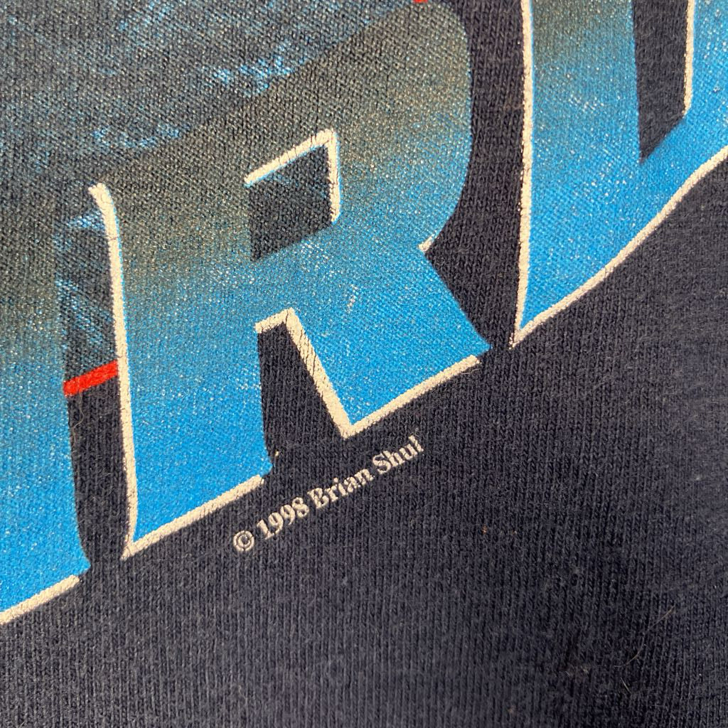Close-up of a graphic design with blue and black colors, featuring the text '1998 Brian Shul'.