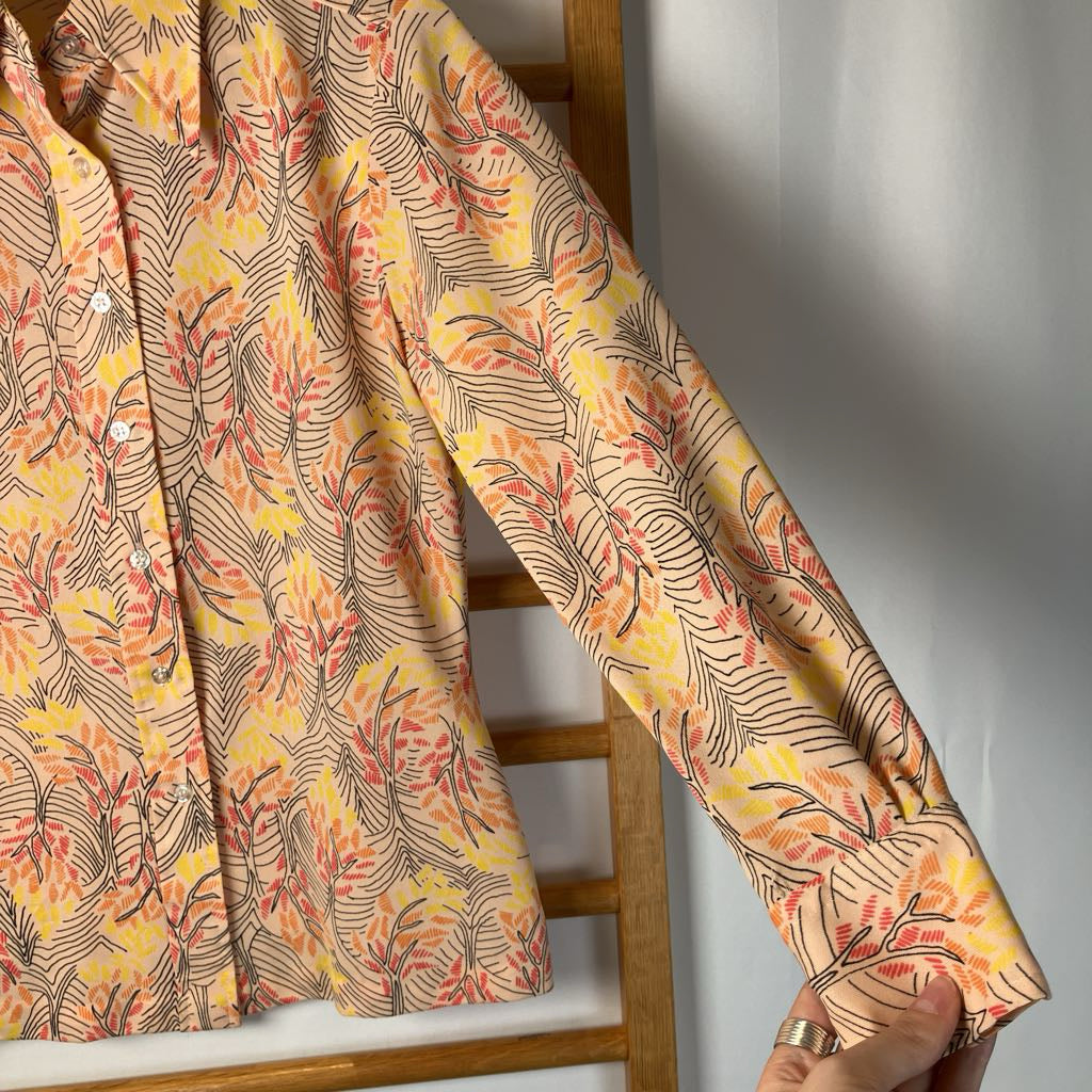 Floral patterned fabric shirt draped over a wooden frame against a neutral background