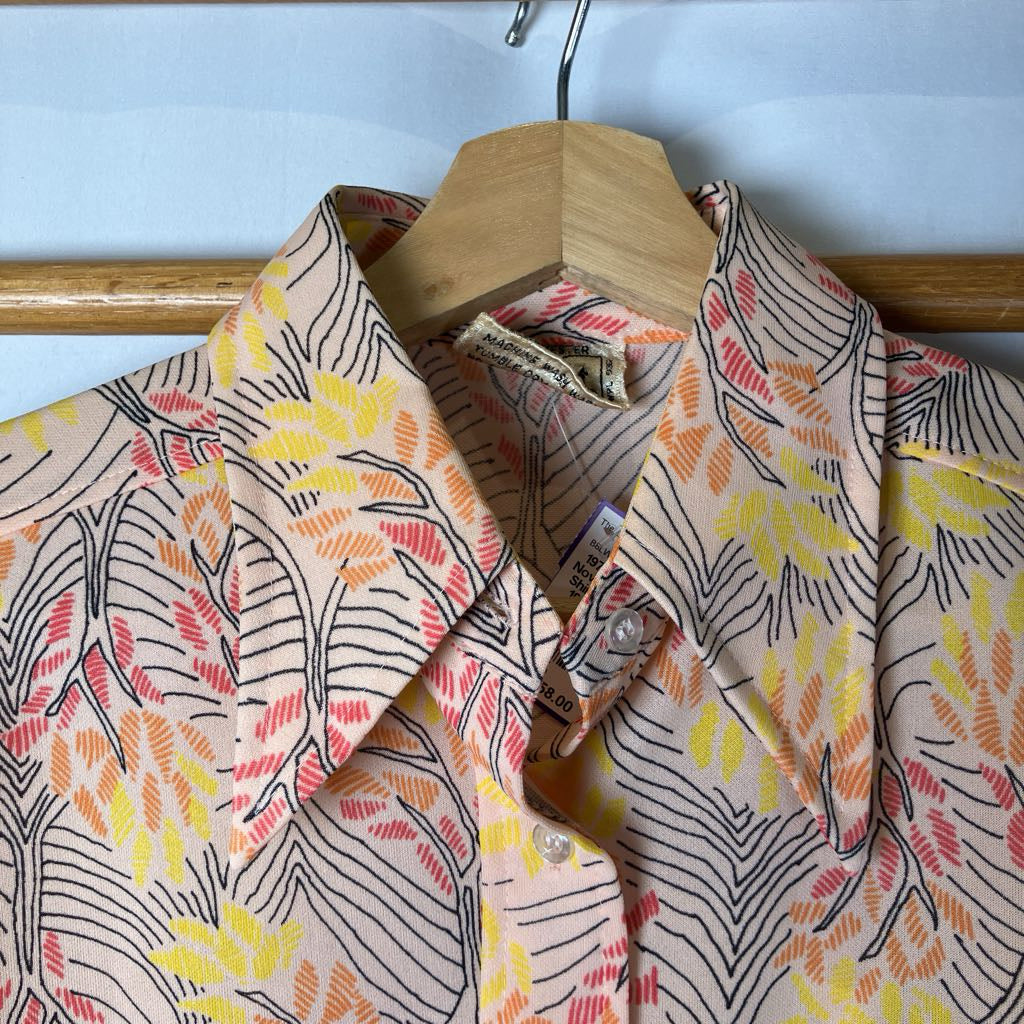 Floral patterned shirt on a hanger against a light blue wall.
