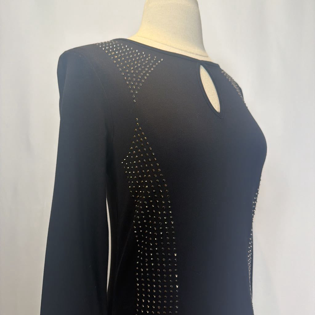 Black dress with rhinestone embellishments on a mannequin in front of a white wall.  