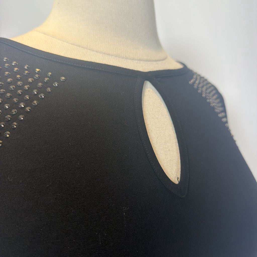 Black dress with rhinestone embellishments on a mannequin in front of a white wall.  