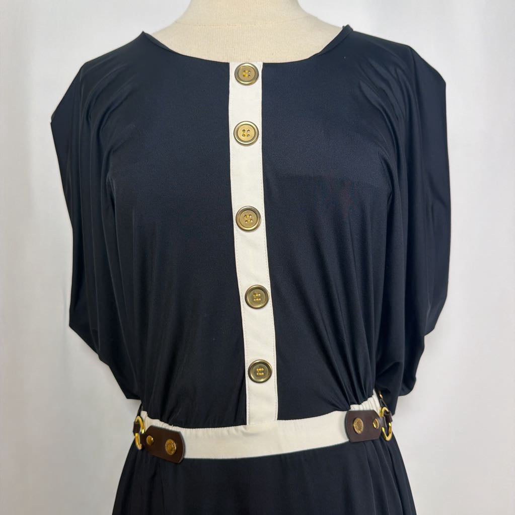 black dress with gold button details against white backdrop