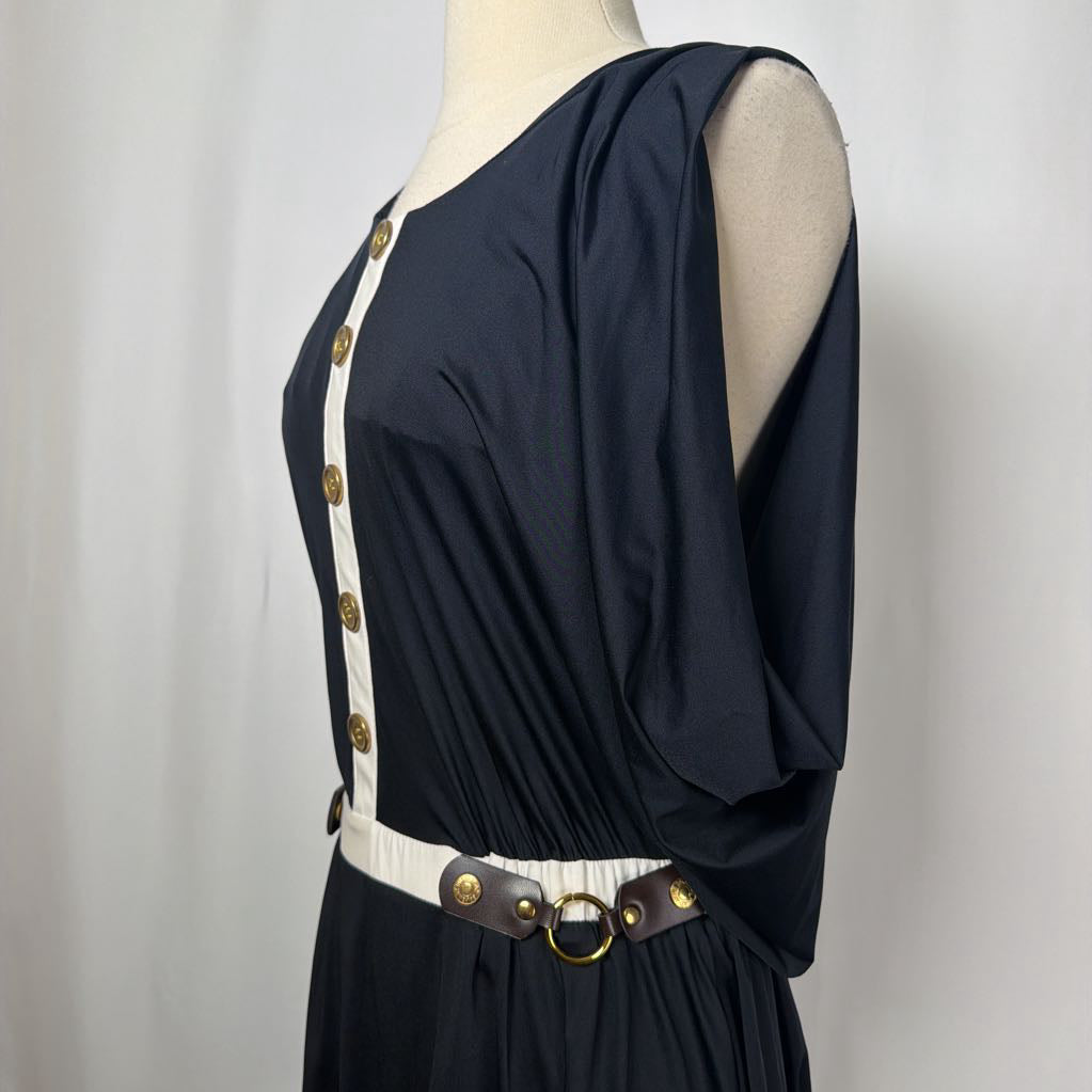 black dress with gold button details against white backdrop