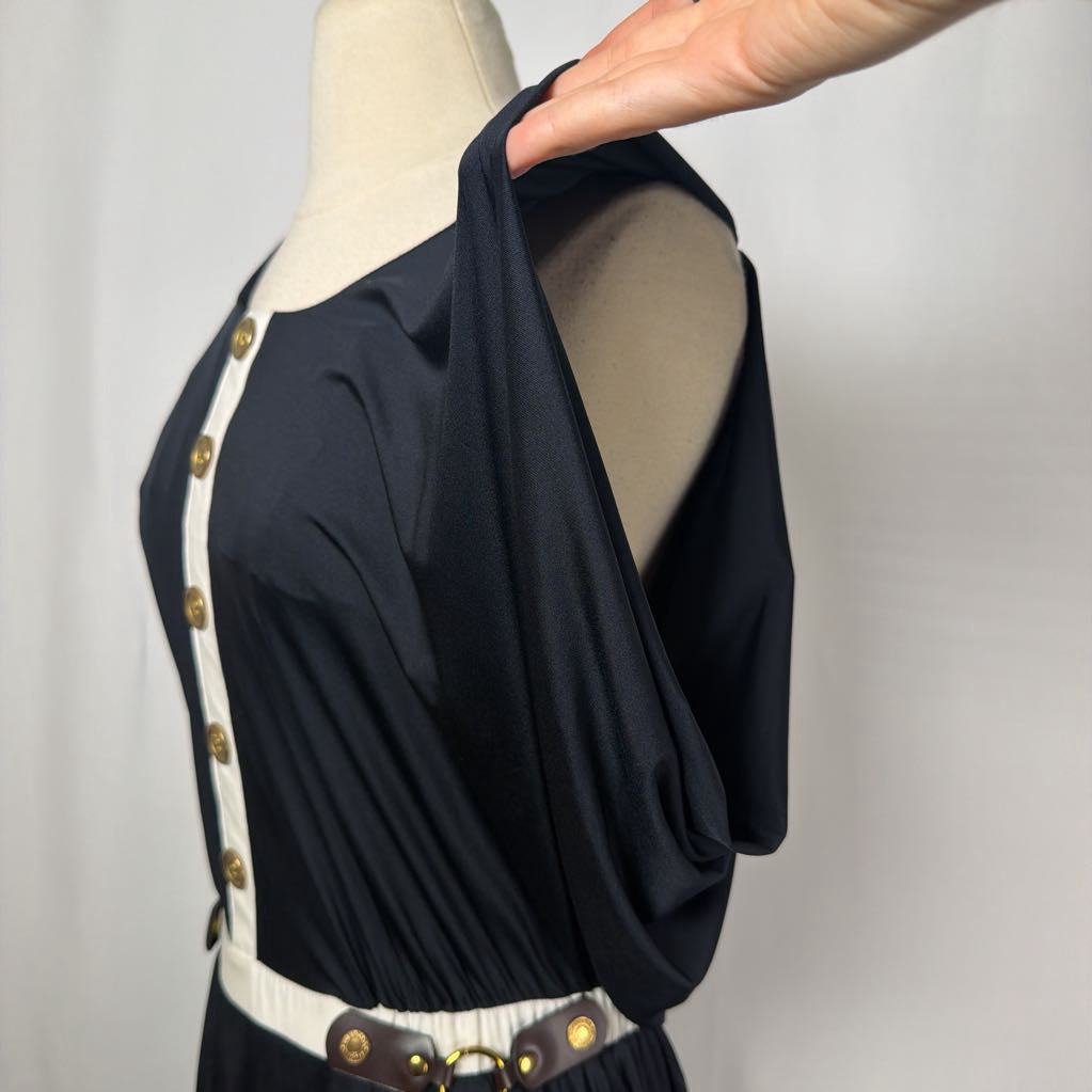 black dress with gold button details against white backdrop
