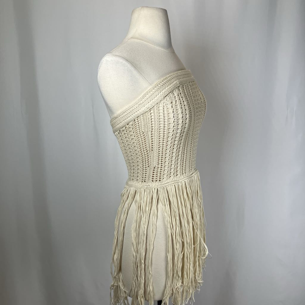 Beige knitted dress with fringe on a mannequin against a plain background