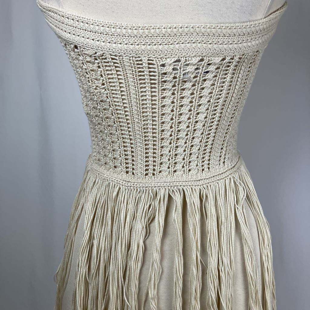 Beige crochet dress with fringe details on a gray background