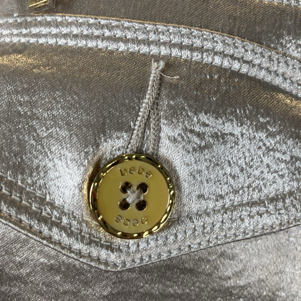Close-up of a gold button on a silver metallic fabric background