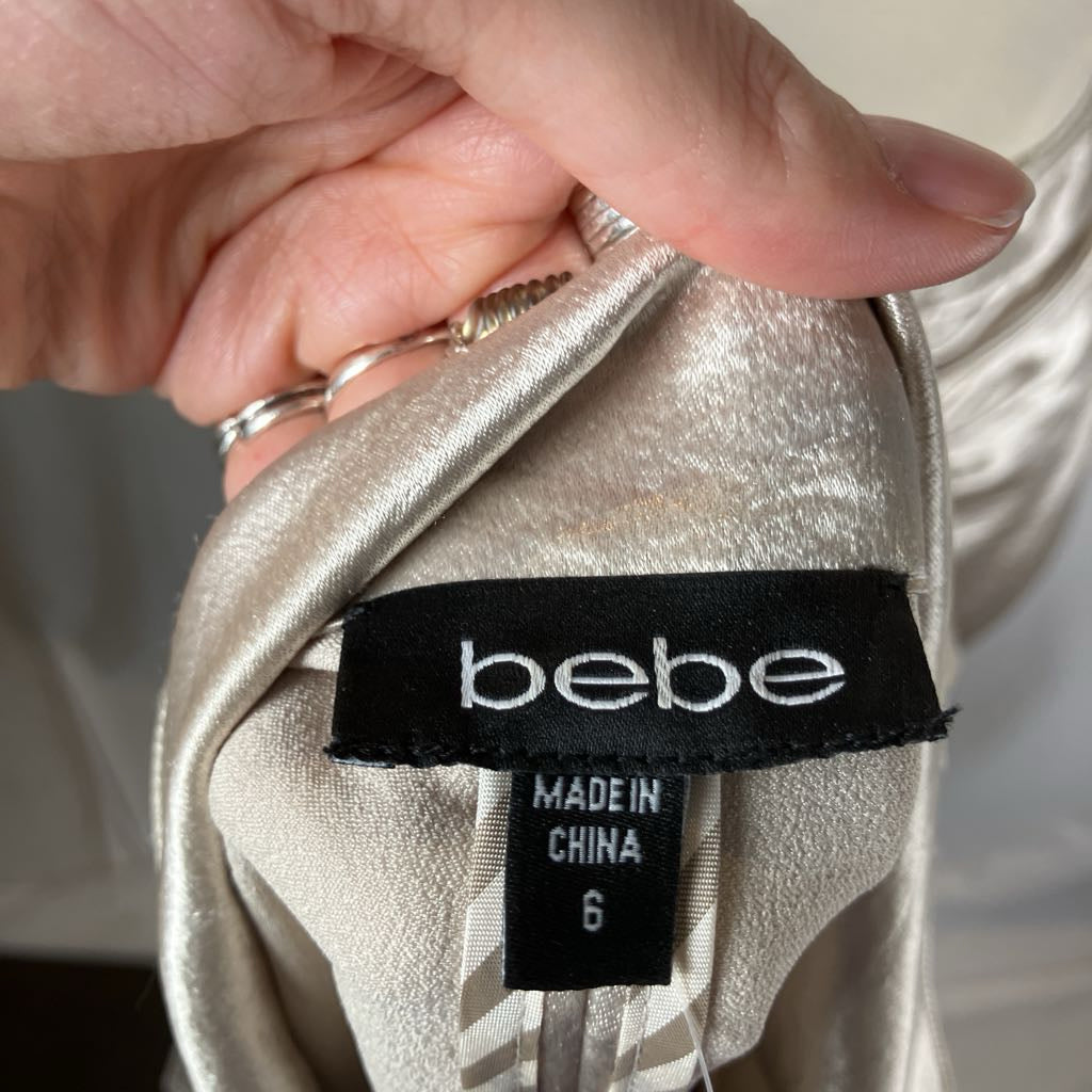 Close-up of a 'bebe' label on a piece of fabric with a hand holding it.