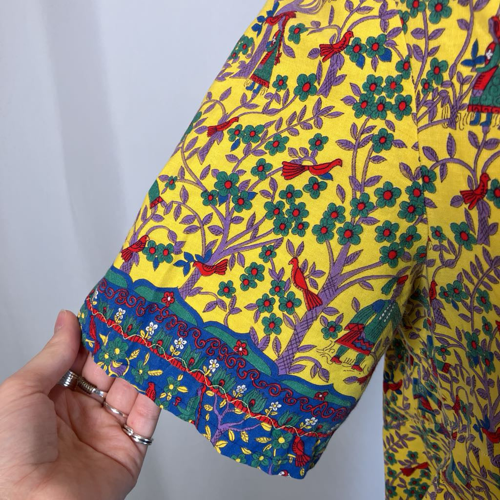 Colorful fabric with intricate patterns and a hand holding it against a white background