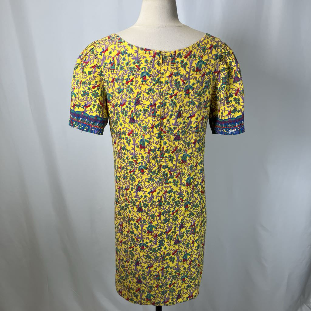 Yellow dress with colorful pattern on a mannequin against a plain background