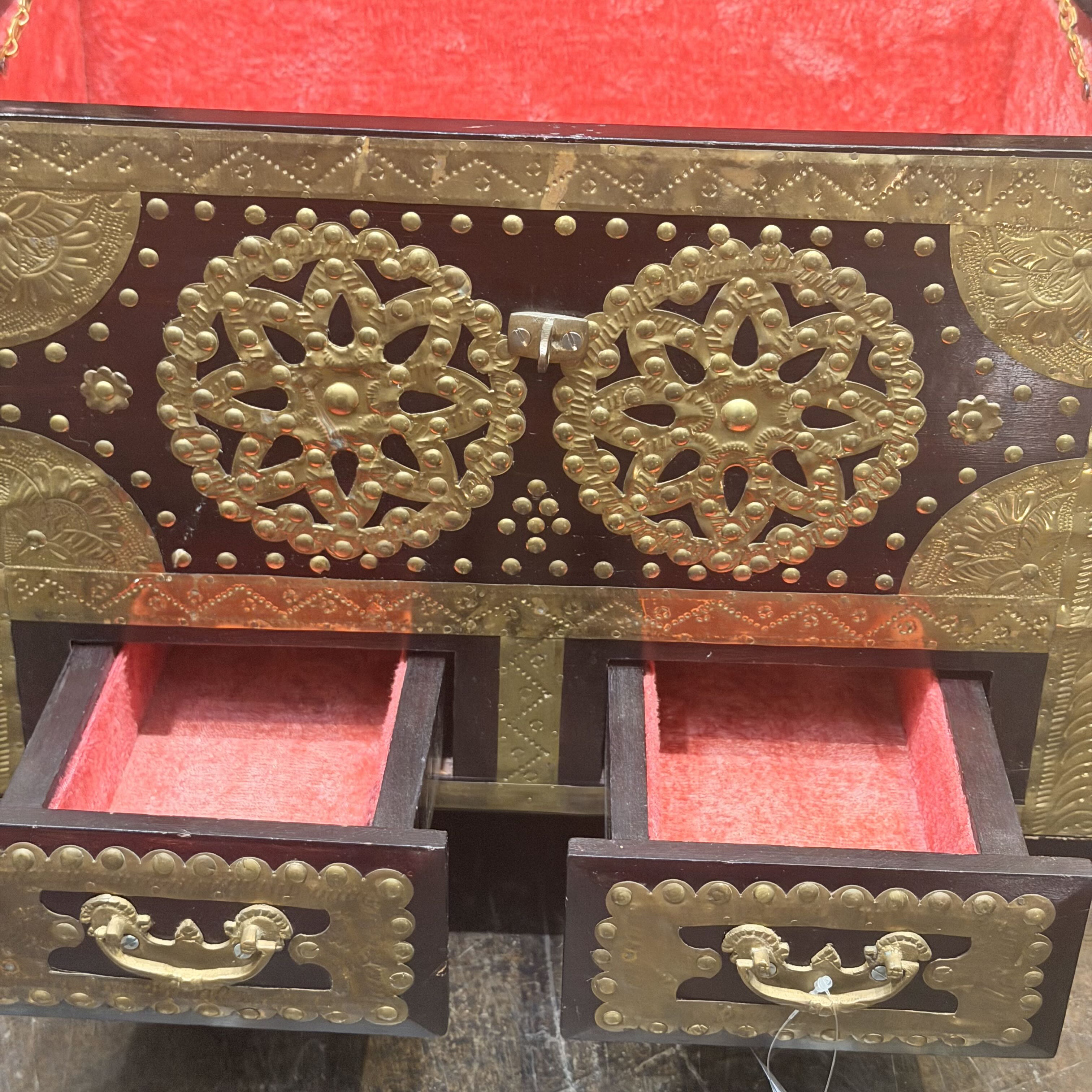 Decorative jewelry box with gold embellishments and open drawers on a red background
