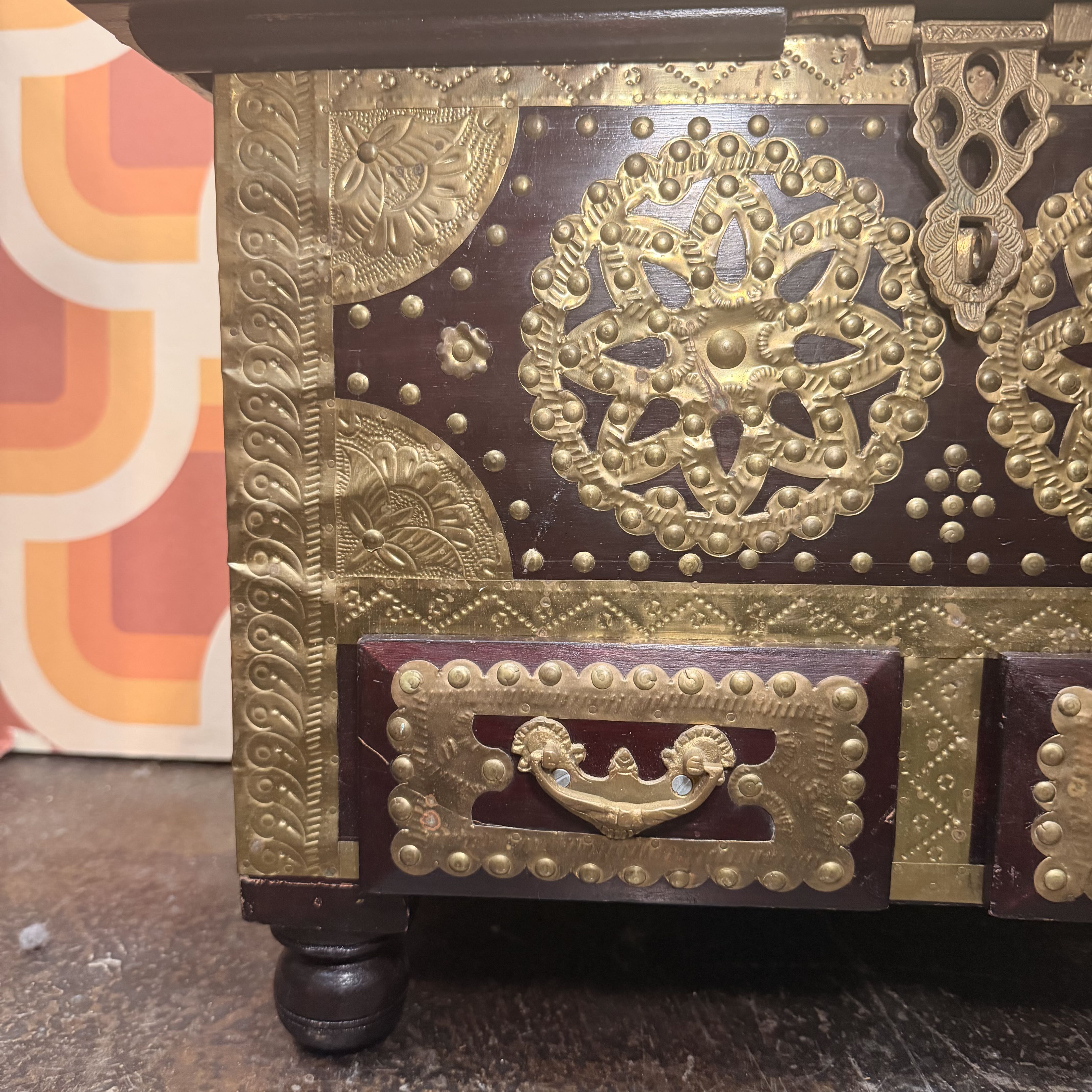 Decorative wooden box with intricate gold patterns on a textured surface.