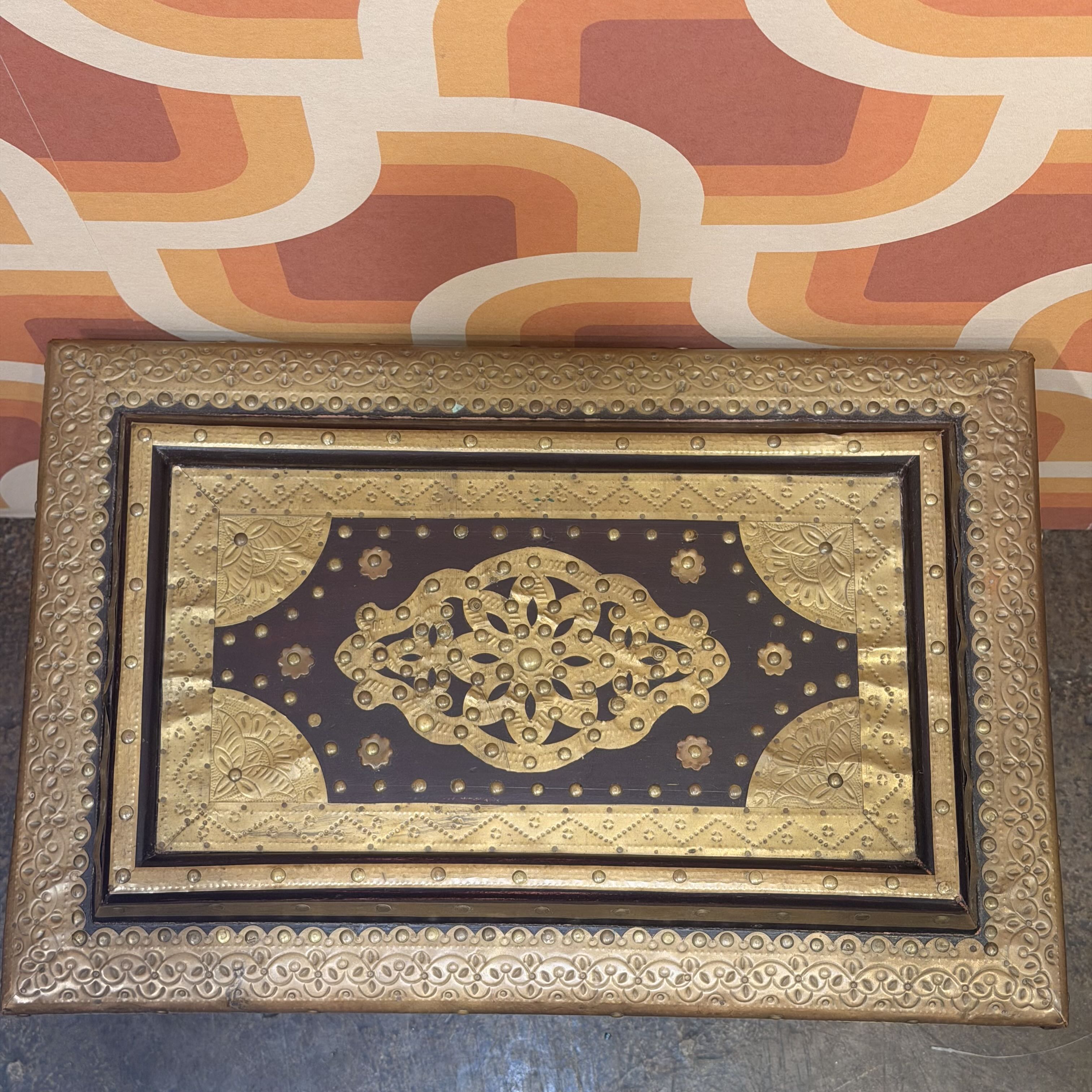 Decorative gold and black plaque with intricate patterns on a patterned background