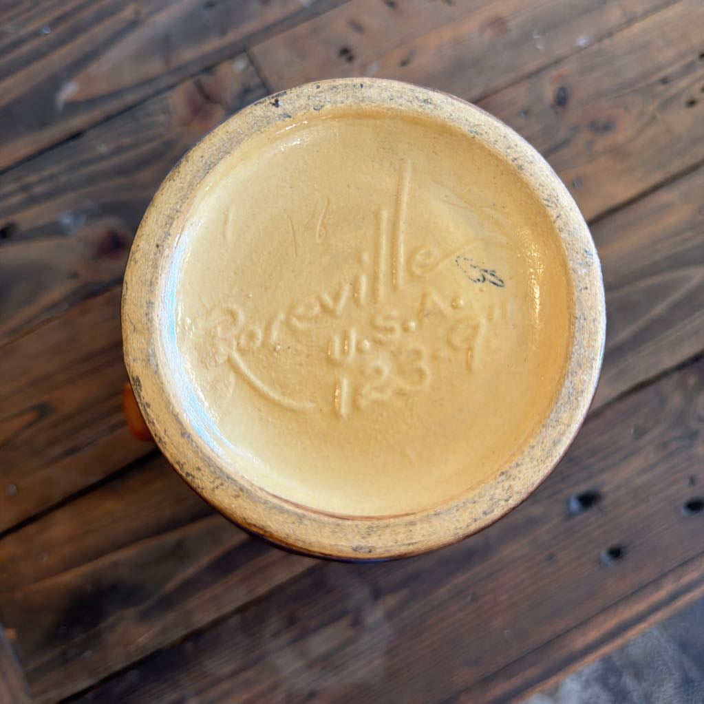 Top-down view of a round ceramic plate or dish with a light tan glazed center and a speckled brown rim, resting on a dark wooden surface. The center is embossed with the text 'Boreville U.