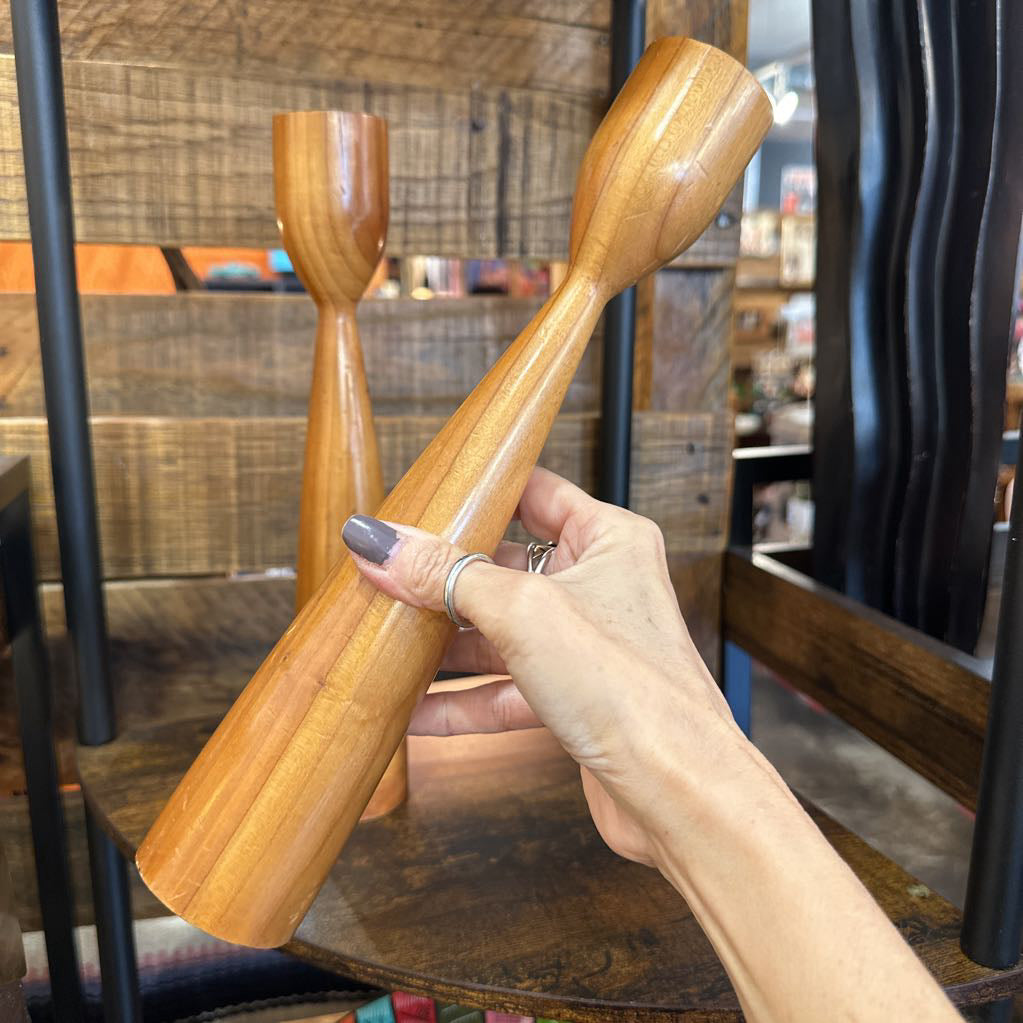 Hand holding a wooden ladle with a blurred indoor setting in the background