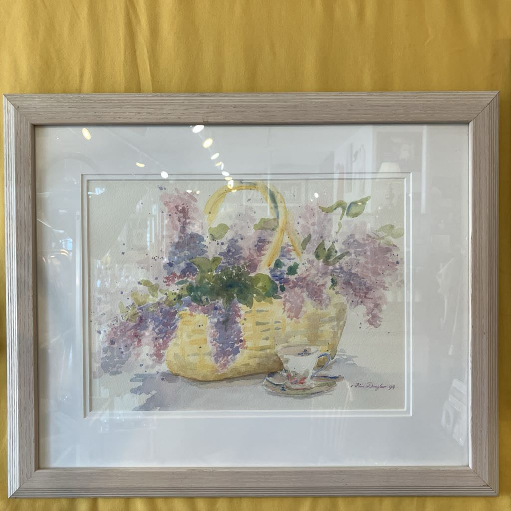 Framed artwork of a basket of flowers with a teacup on a yellow background