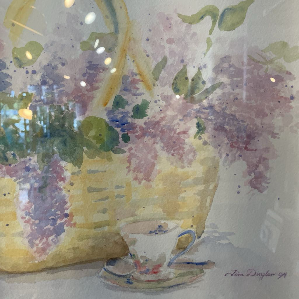 Watercolor painting of a basket with flowers and a teacup on a saucer.