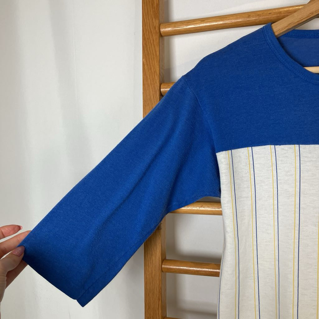 Blue sweater with a striped pattern on a wooden chair against a white background