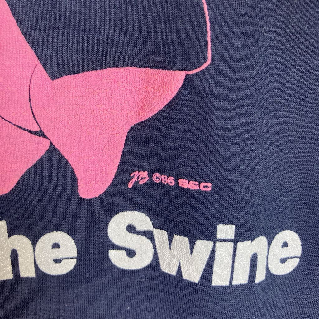 Close-up of a navy blue graphic print featuring a pink shape, small pink text reading '1B CBU SSC', and large white text reading 'he Swine'.