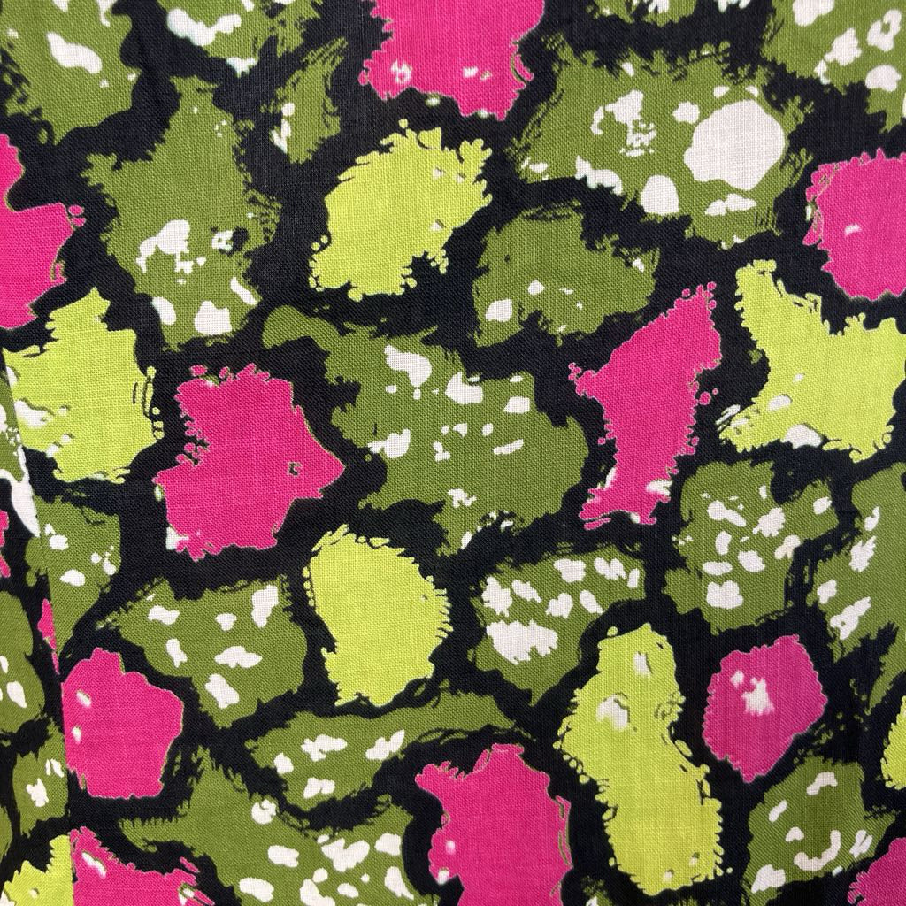 Patterned fabric with pink, green, and white shapes on a black background