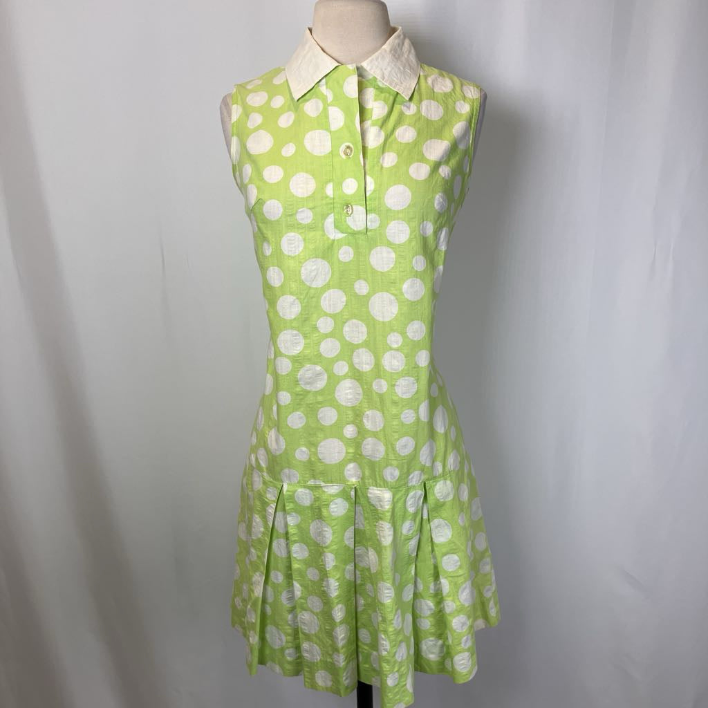 Green dress with white polka dots on a mannequin against a plain background