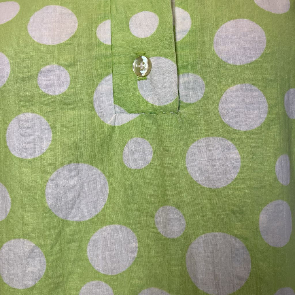 Green fabric with white polka dots and a button detail