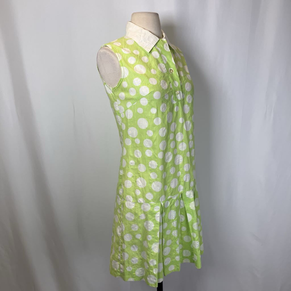 Green dress with white polka dots on a mannequin against a plain background