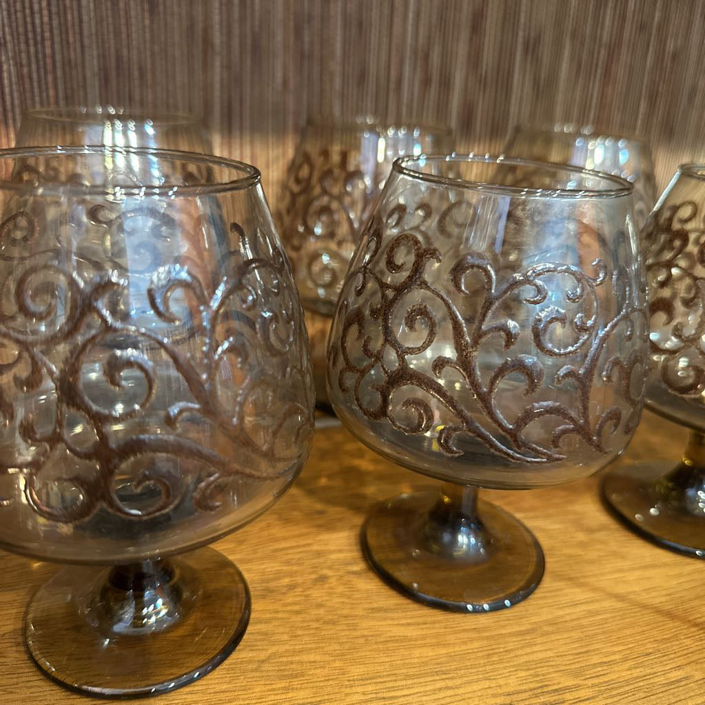Decorative glass goblets with intricate designs on a wooden surface