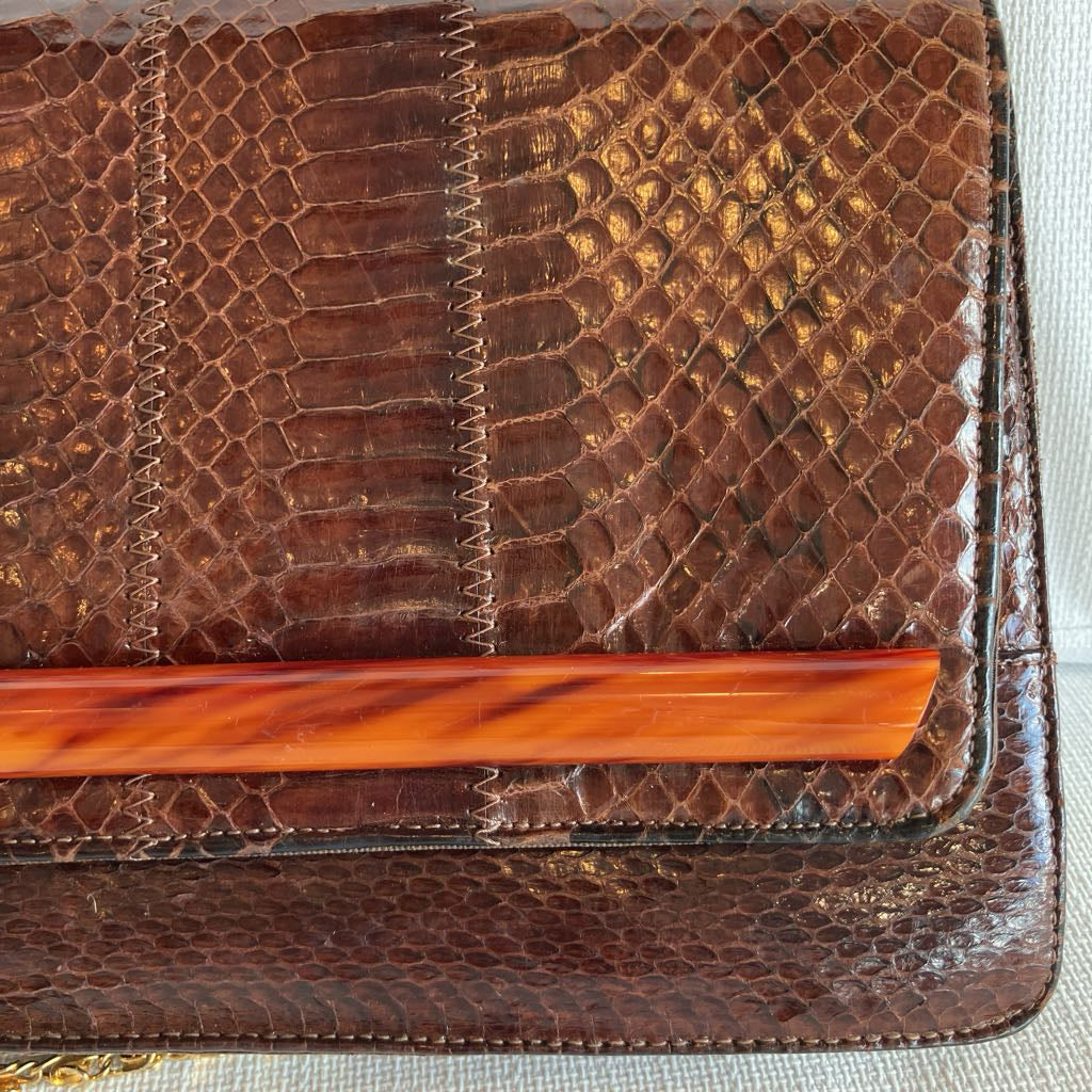 Brown textured clutch bag with a wooden handle on a light background