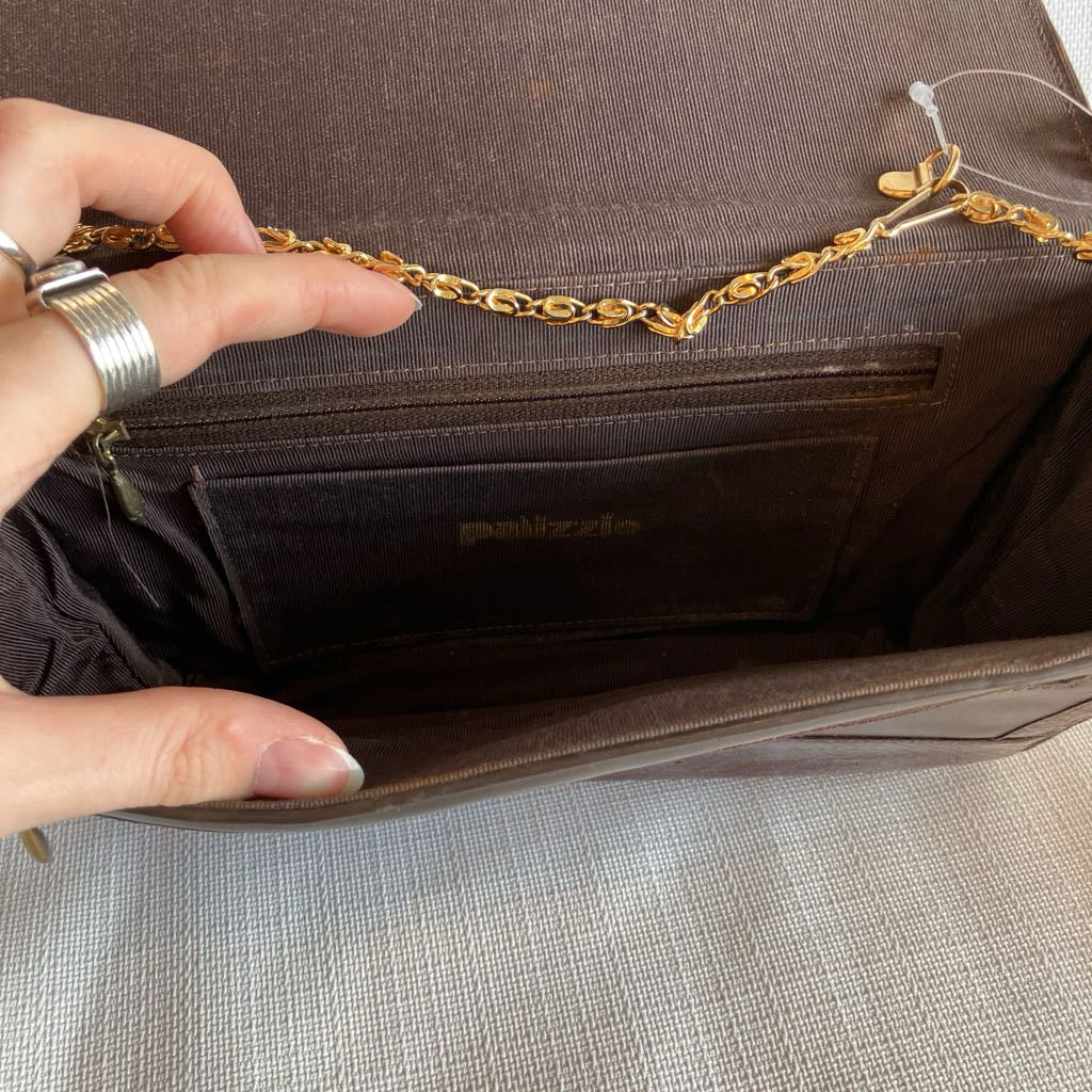 Brown leather bag with gold chain handle held by a hand
