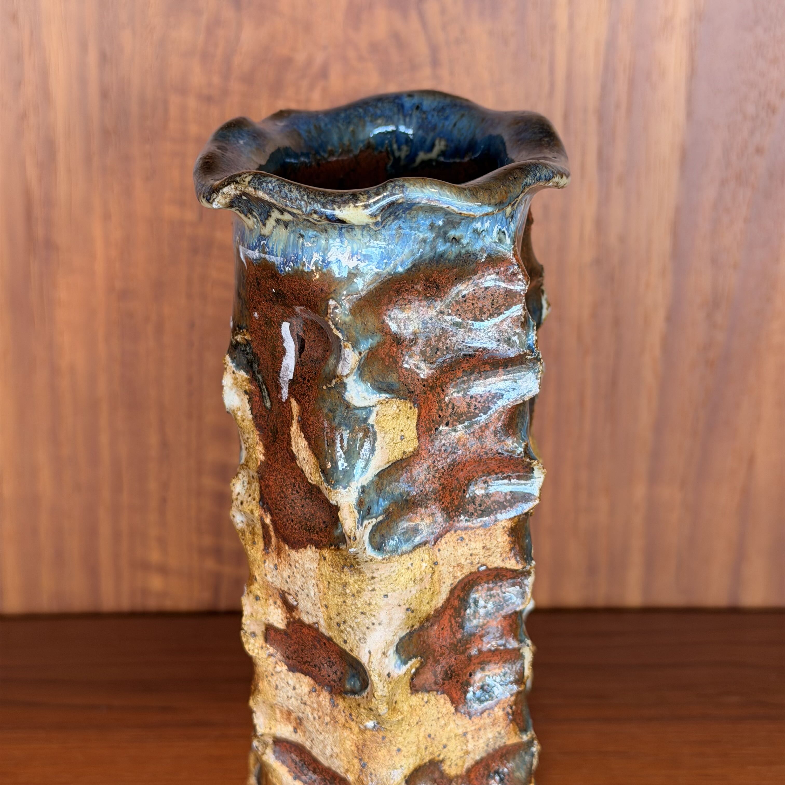 Textured ceramic vase with a wooden background
