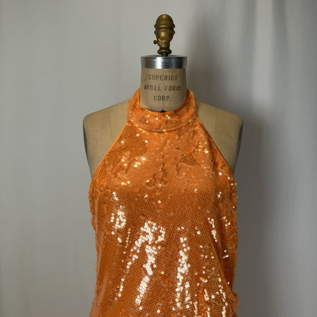 Orange sequin top on a mannequin against a plain background