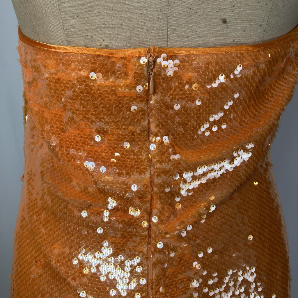 Close-up of a brown sequined garment on a mannequin with a plain background