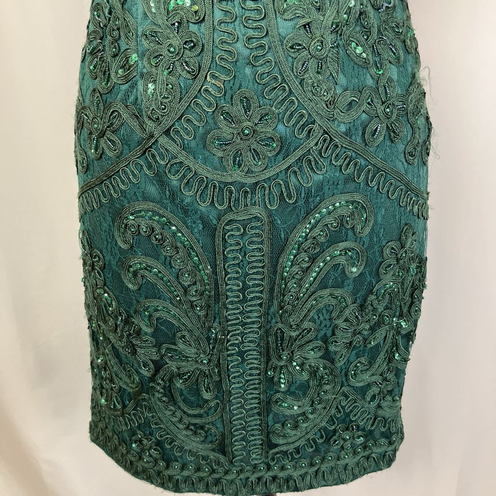 Teal dress with intricate beadwork on a beige background