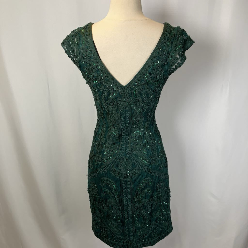 Green beaded dress on a mannequin against a plain background