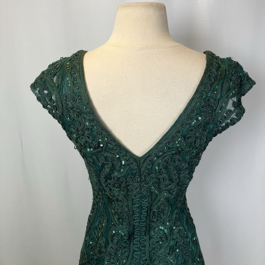 Green lace dress on a mannequin against a plain background