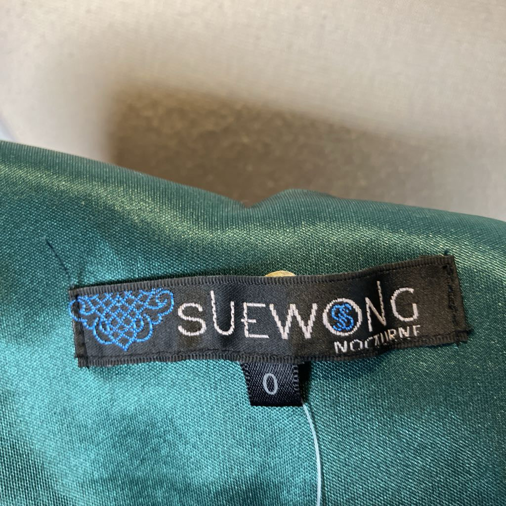 Sue Wong label on a green garment with a white background