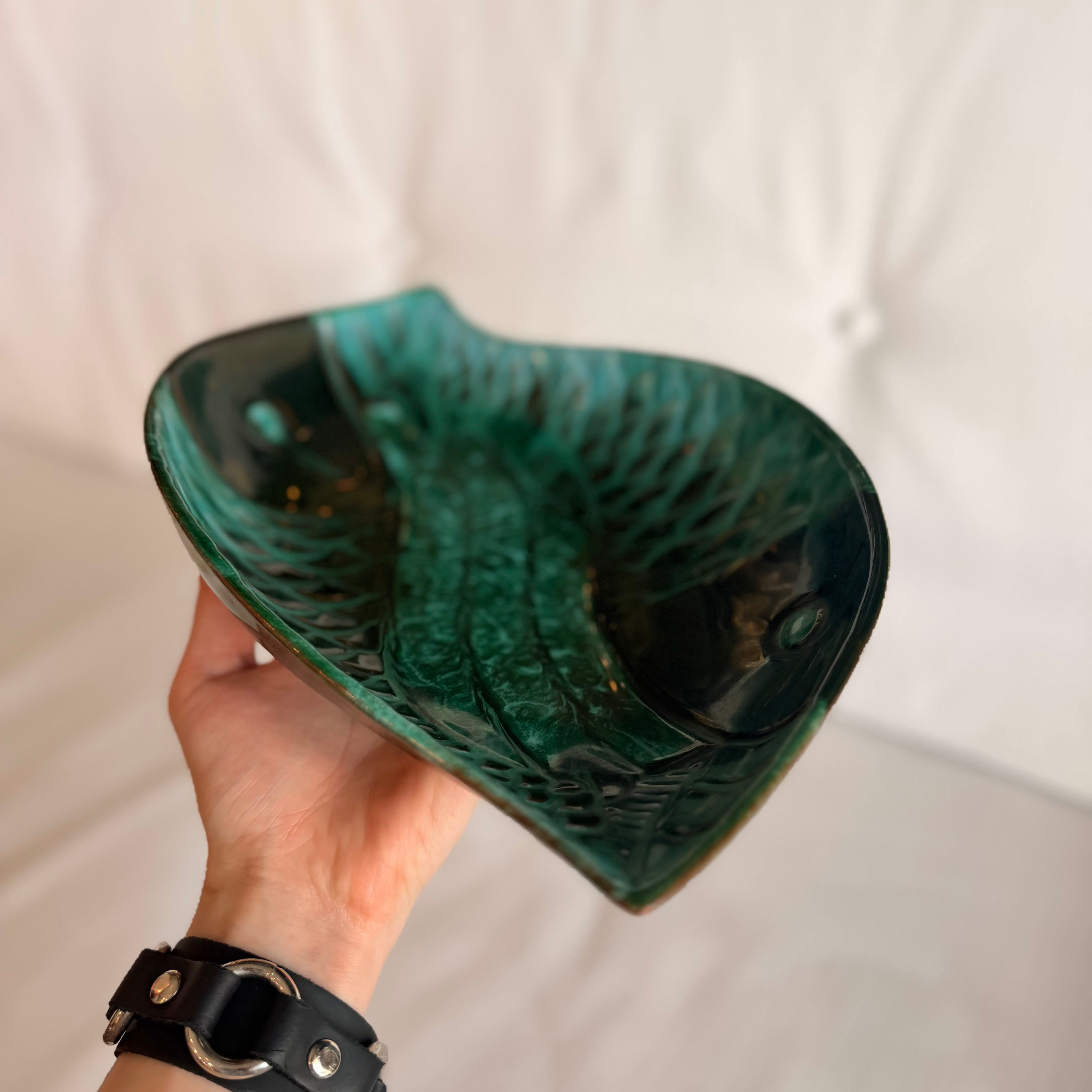 Hand holding a green ceramic bowl with a textured surface against a white background