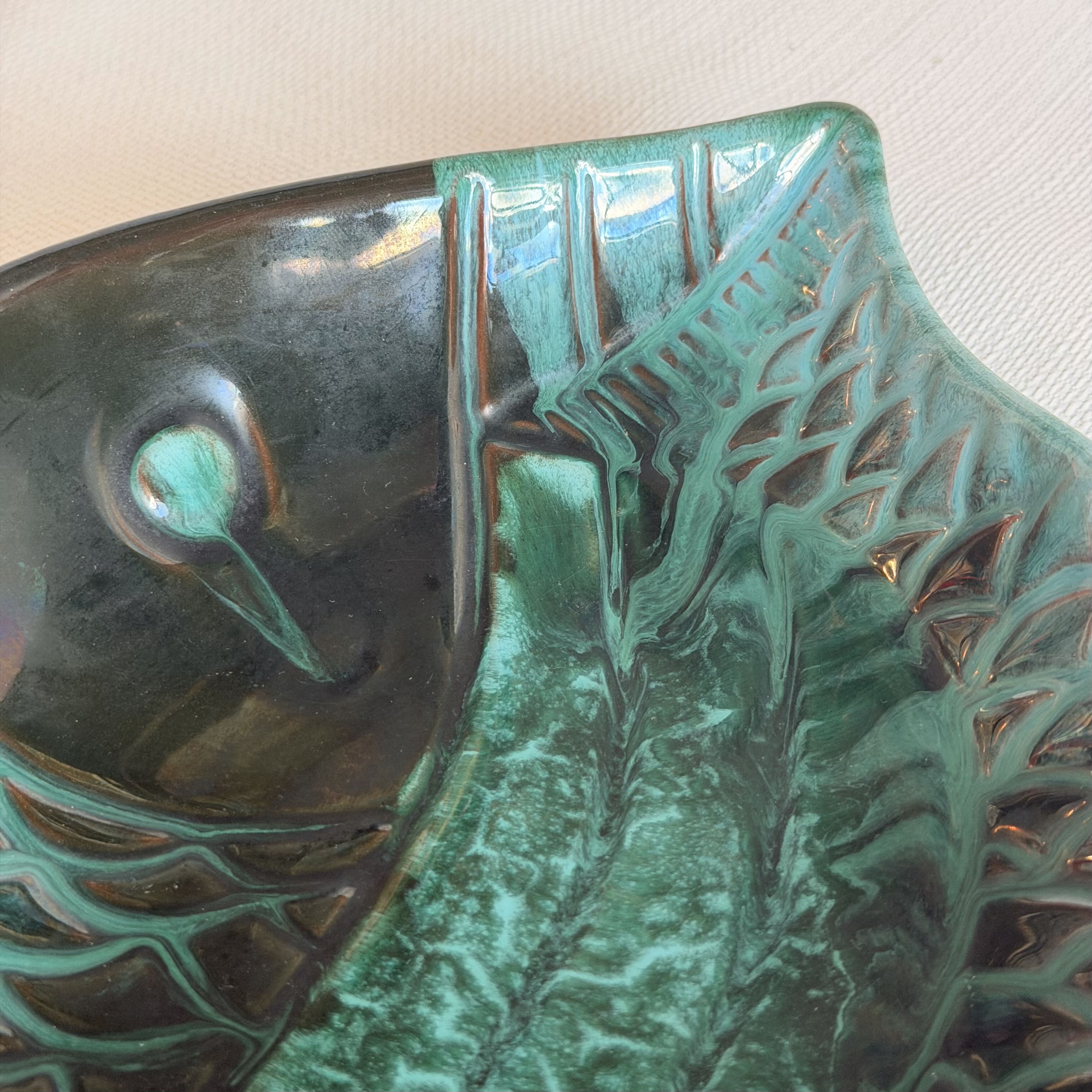 Ceramic fish-shaped object with green and brown glaze on a white background