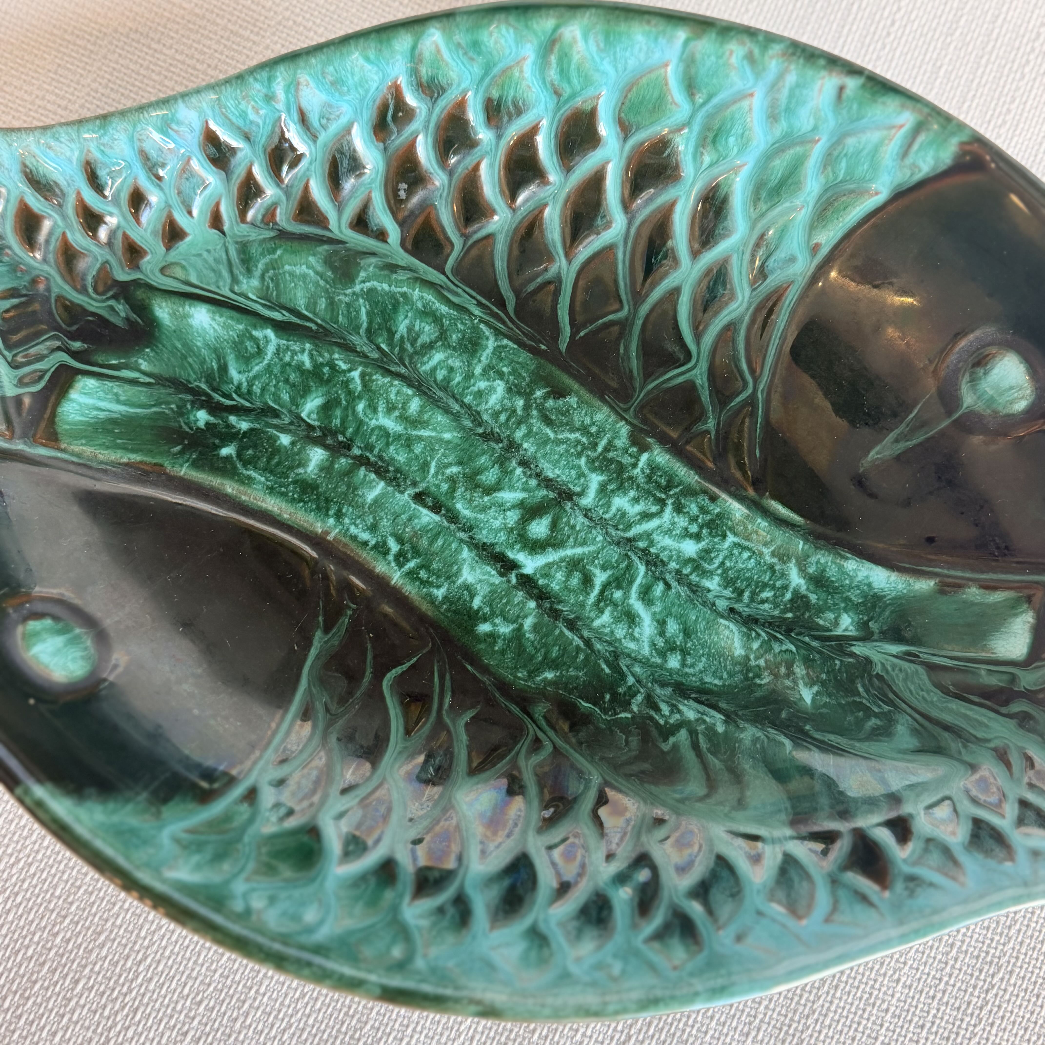 Decorative ceramic leaf with textured surface on a light background