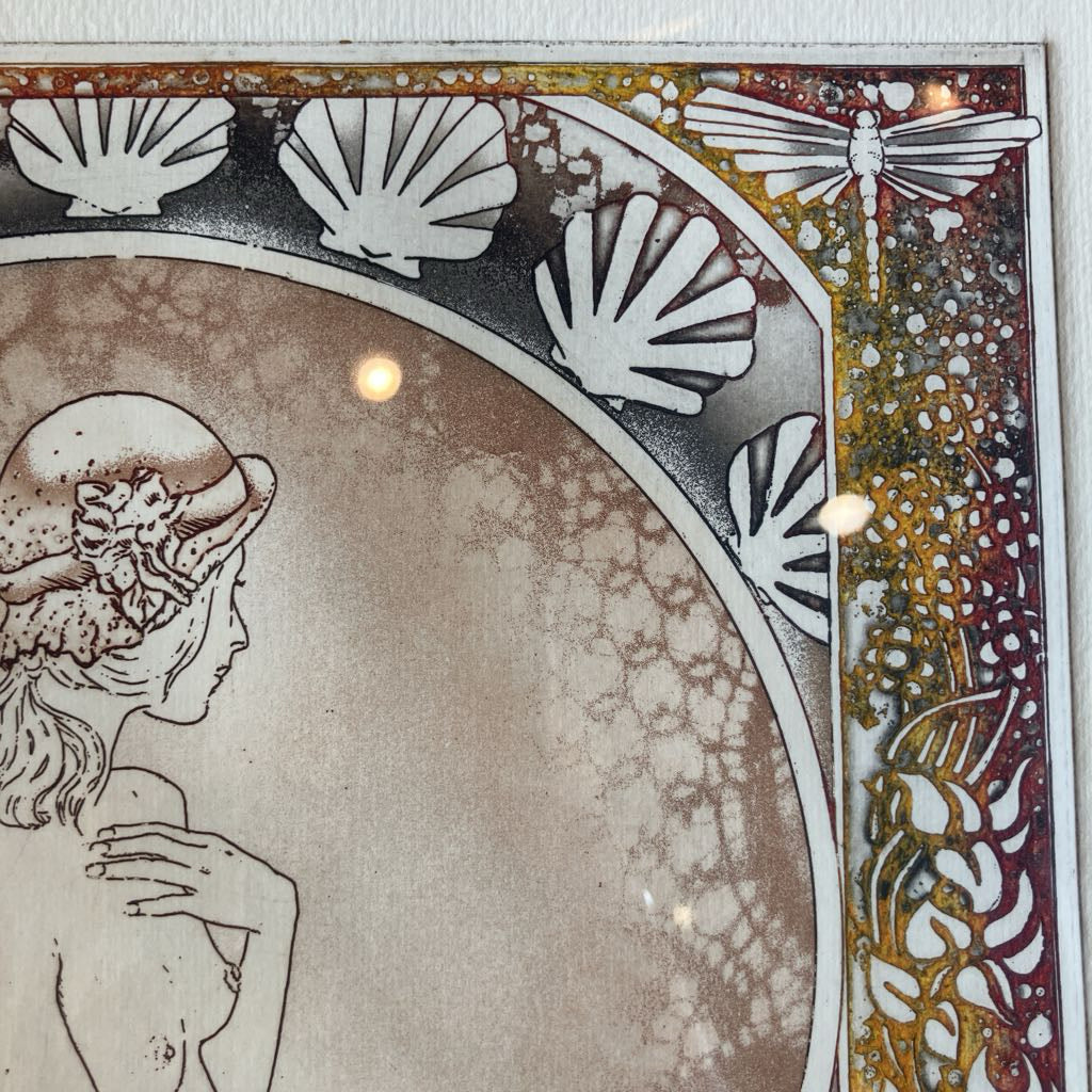 Decorative artwork with a woman's profile, shells, and dragonflies in a stylized border.