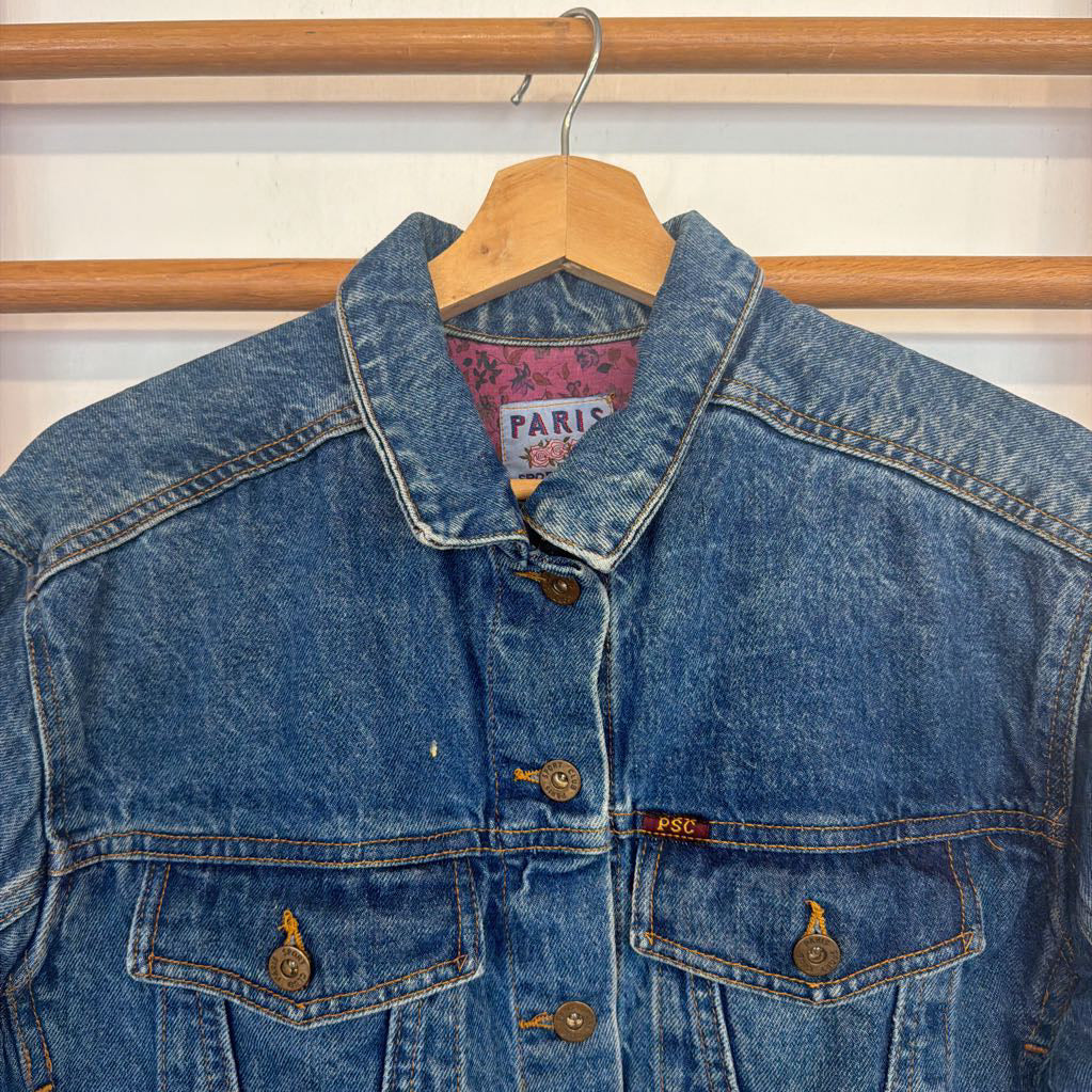 Blue denim jacket on a hanger with a striped background