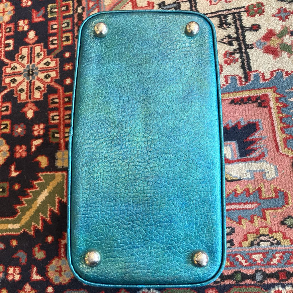 Blue leather suitcase with silver studs on a patterned rug